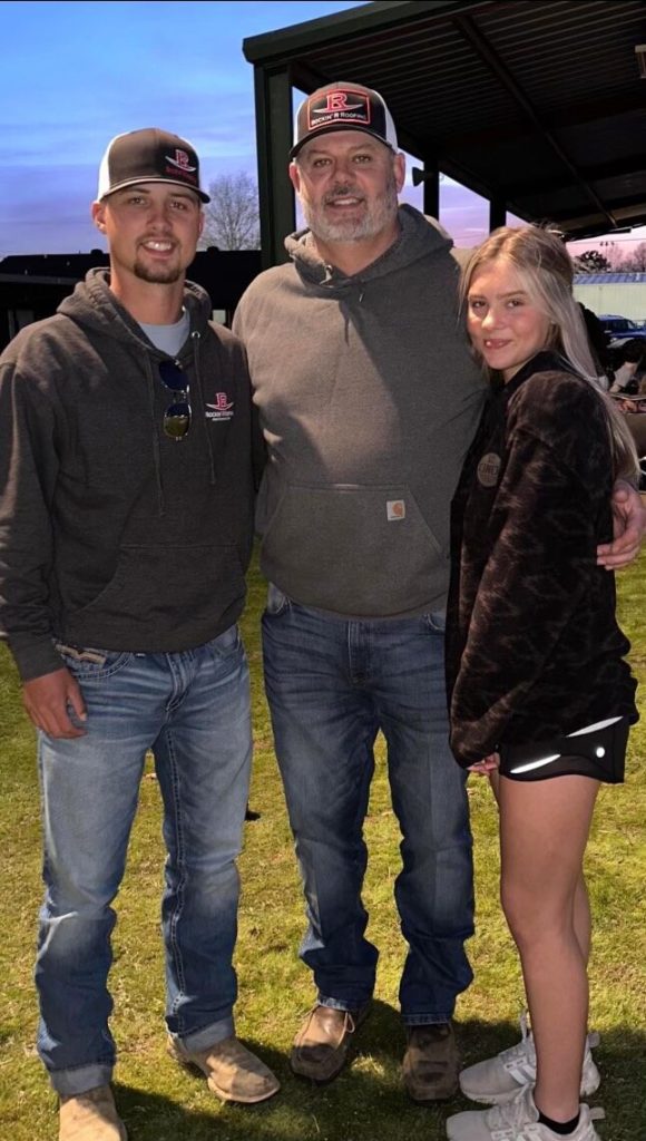 two men and a woman standing together in a field