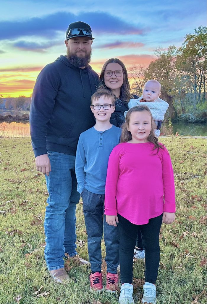 man, woman, and 3 children standing in a field